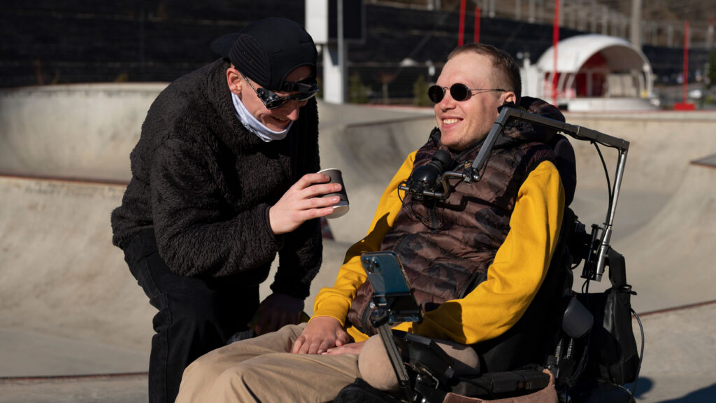 Man in wheelchair with high intensity support carer