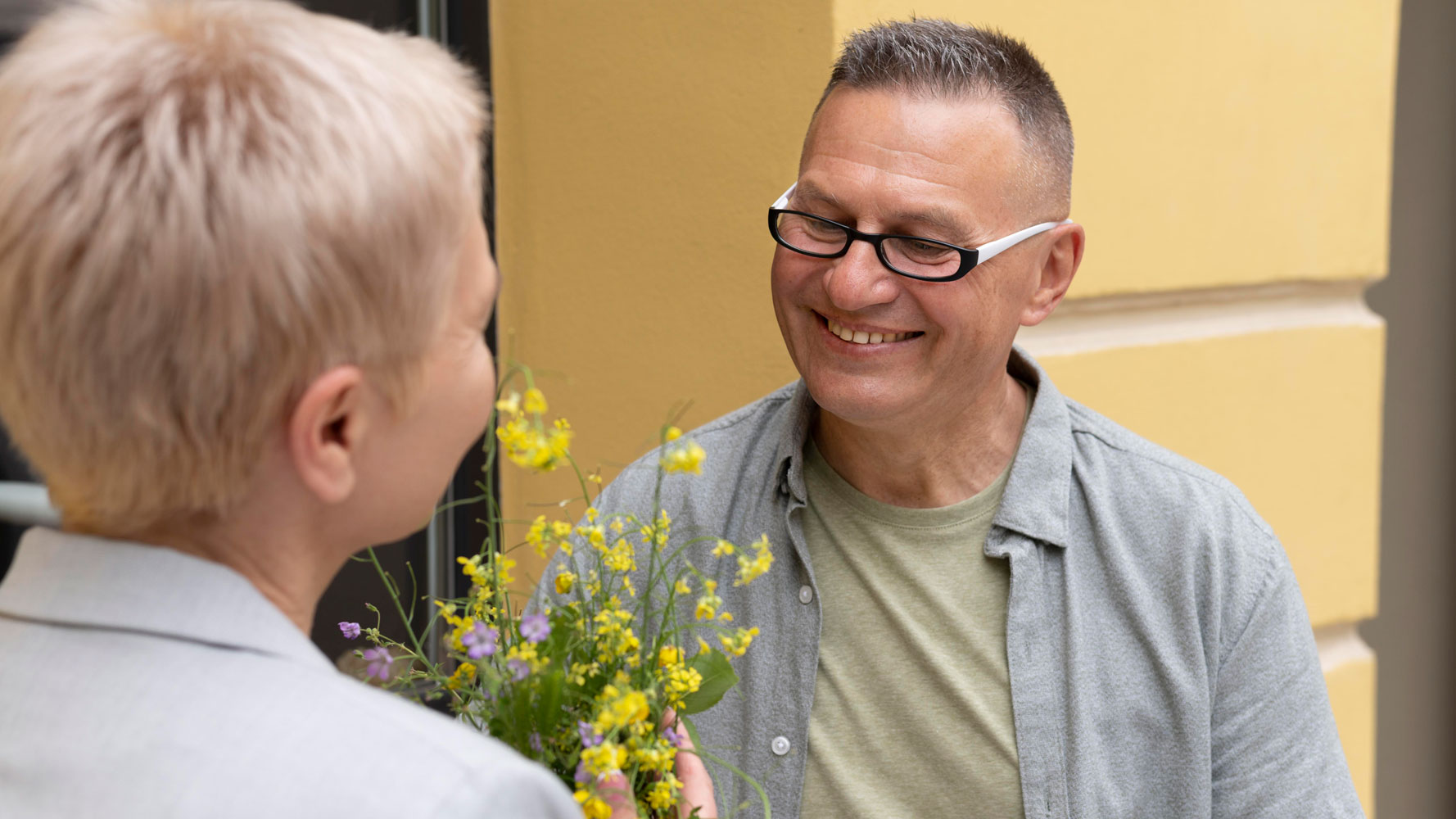 Man wearing glasses with woman and yellow flowers